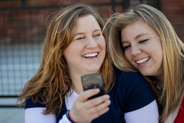 photo of two women looking at a cell phone and sharing a laugh