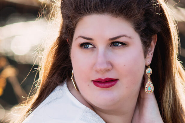Portrait of a woman outdoors in warm autumn light, looking to the side with soft expression and colorful earrings.